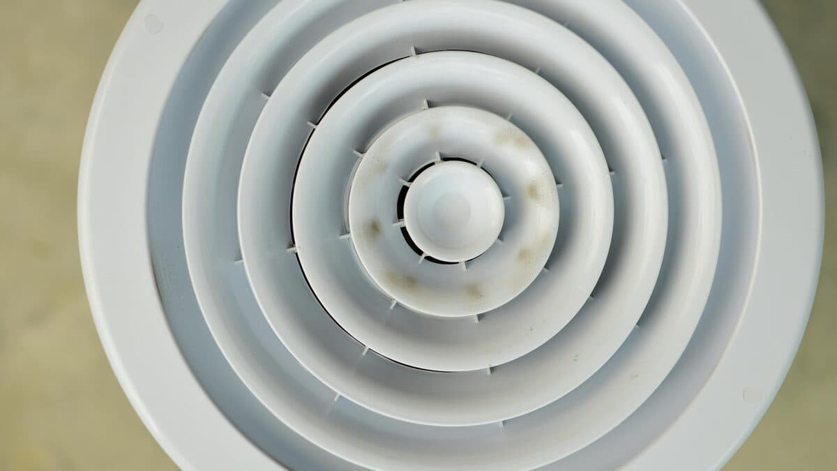 White circular ceiling air vent viewed from below, showing concentric rings with slight discoloration